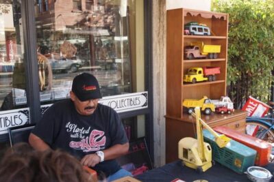 A man selling old metal trucks on the sidewalk in Old Towne Orange, CA.