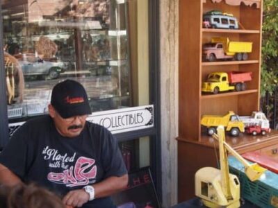 A man selling old metal trucks on the sidewalk in Old Towne Orange, CA.