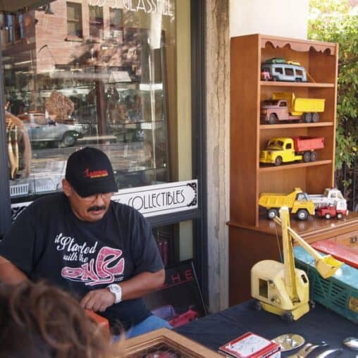 A man selling old metal trucks on the sidewalk in Old Towne Orange, CA.