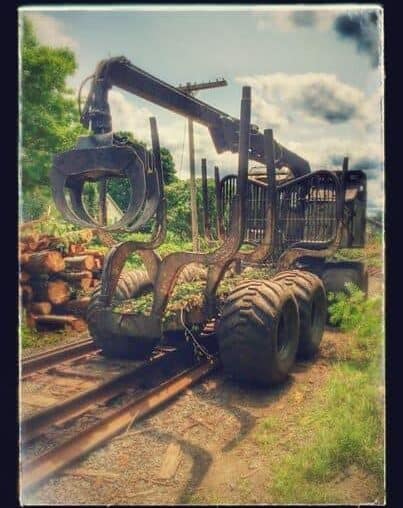 A logging machine takes a turn and then heads right down the railroad tracks today in South Deerfield, MA.