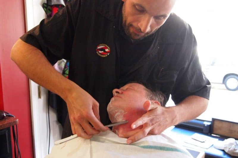 Faraj Capistrano shaving a customer.