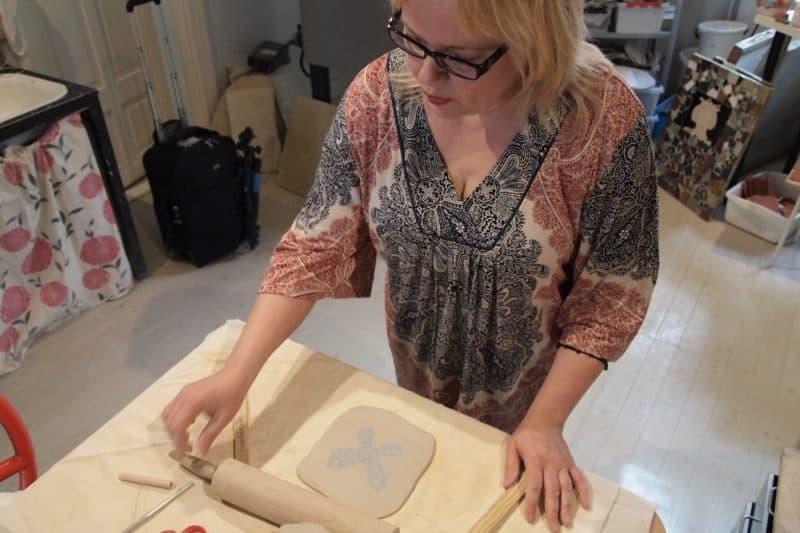 Minna Komulainen places a doily in wet clay to form relief impressions in tiles in her Turku studio.