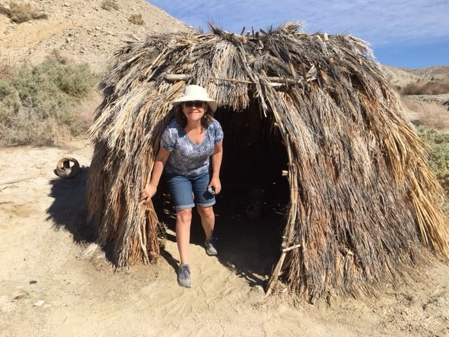 Mary exits a replica of a Cahuilla Indian village hut.