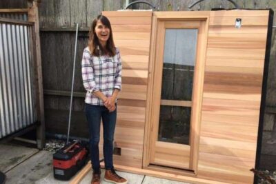 Julie Cox shows off what will soon be their new sauna at her surfer's gathering place in Pacifica called Traveler.